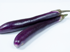 Fresh Chinese eggplant on a white background, showcasing its glossy purple skin.