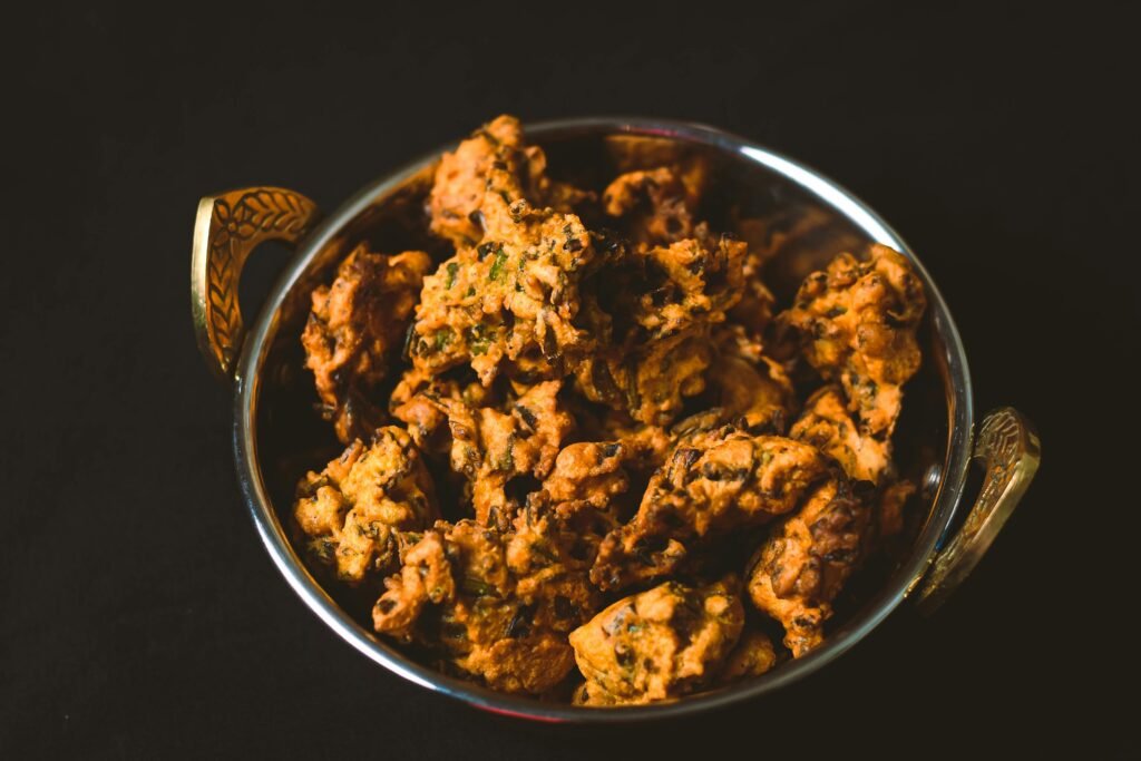 Delicious Indian pakoda served in a traditional metal bowl, showcasing vibrant flavors and texture.