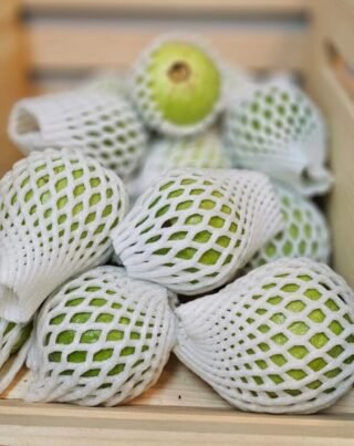 Fresh guavas on a wooden table, showcasing their vibrant color and texture.